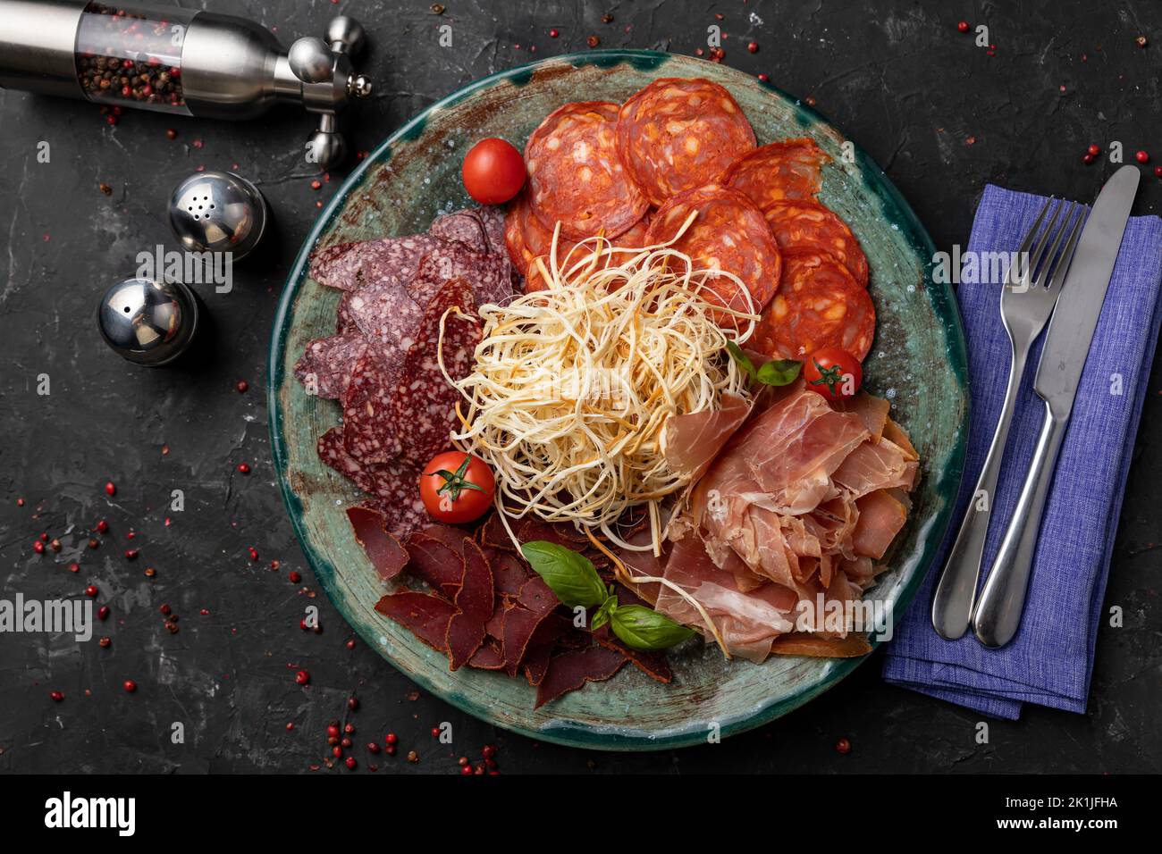 Un primo piano di antipasto di carne con maiale e coltello su fondo nero Foto Stock