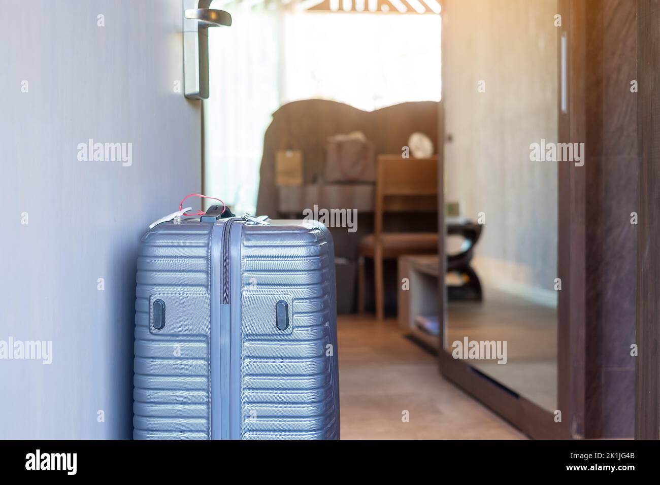Bagagli grigi nelle moderne camere dell'hotel dopo l'apertura della porta. Tempo di viaggio, viaggio, viaggio e concetti di vacanza Foto Stock