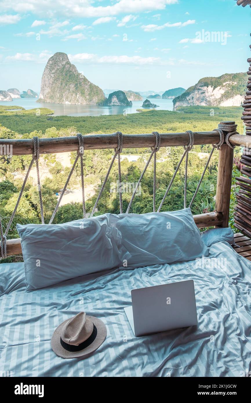 Laptop e cappello contro lo sfondo della baia di Phang Nga, turisti che si rilassano in un resort tropicale a Samet Nang She, vicino a Phuket nel sud della Thailandia. Sud-est A Foto Stock