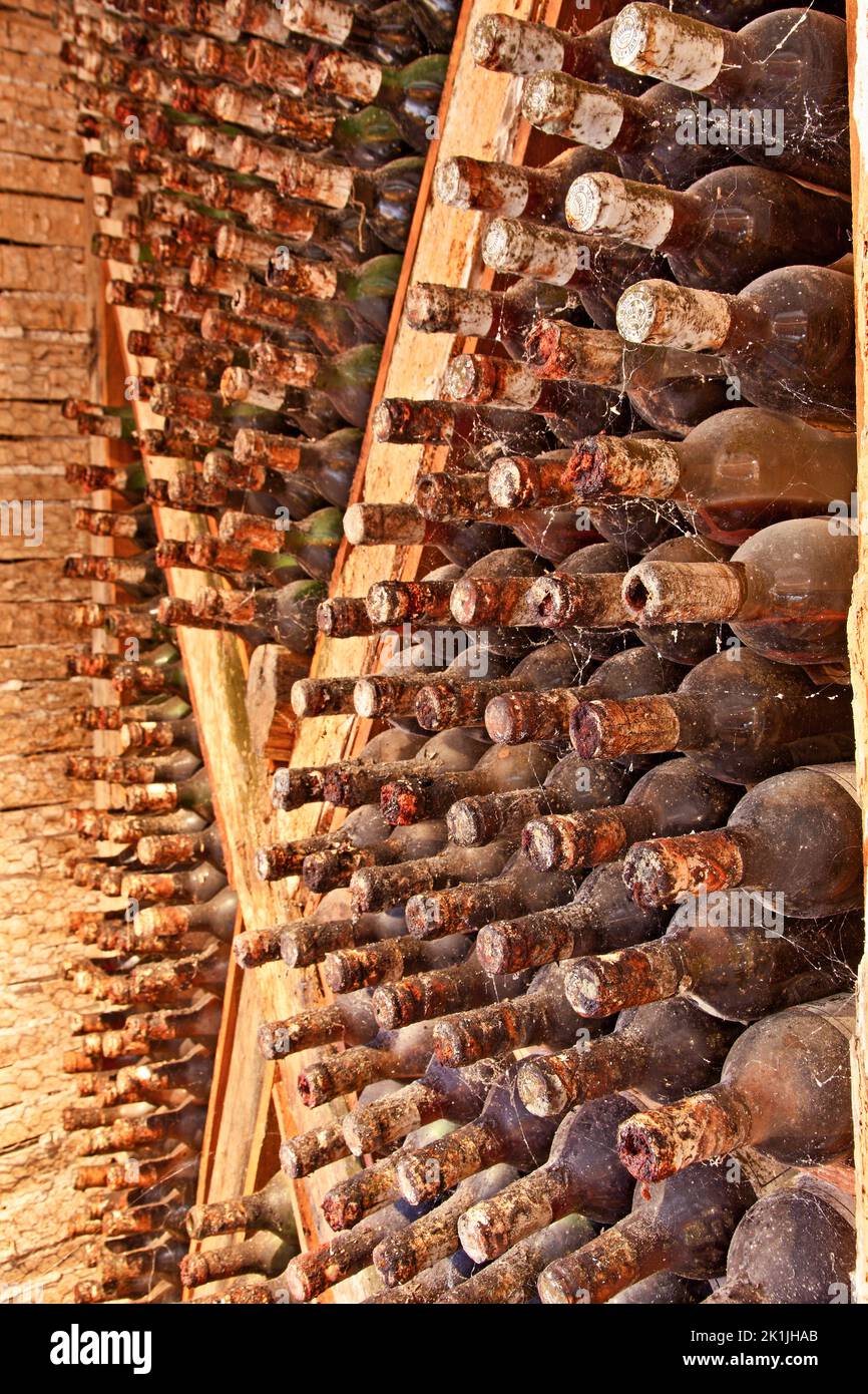 Vecchia cantina con travi in legno e decine di vecchie bottiglie di vino polverose, che maturano in pace in una cantina da qualche parte nell'isola di Zante, in Grecia. Foto Stock