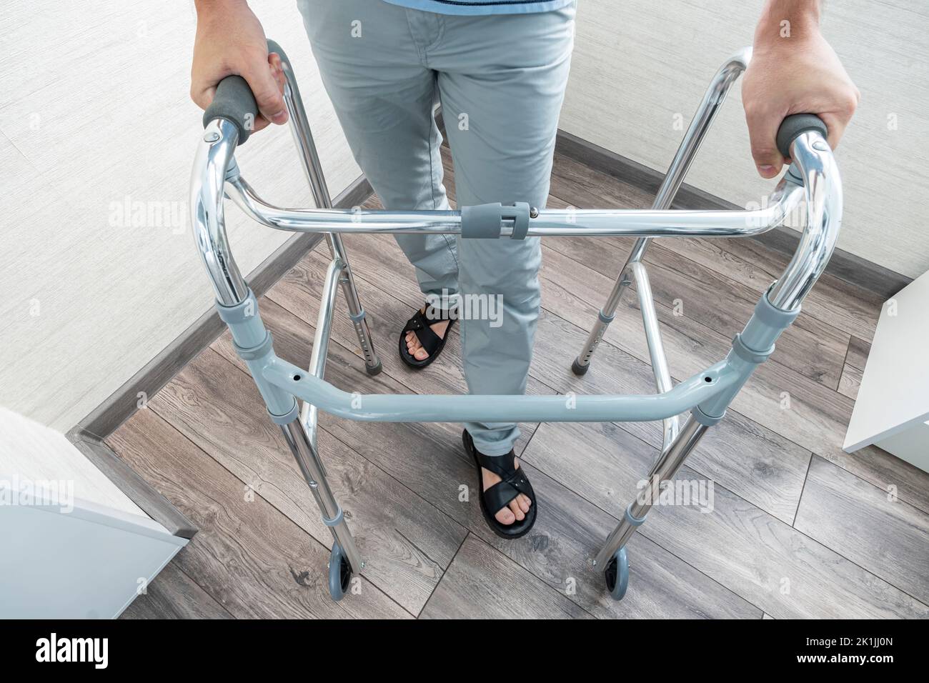 una persona malata cammina con l'aiuto di speciali dispositivi per la riabilitazione. Escursionisti per adulti. Riabilitazione dopo una gamba rotta o ictus. Foto Stock