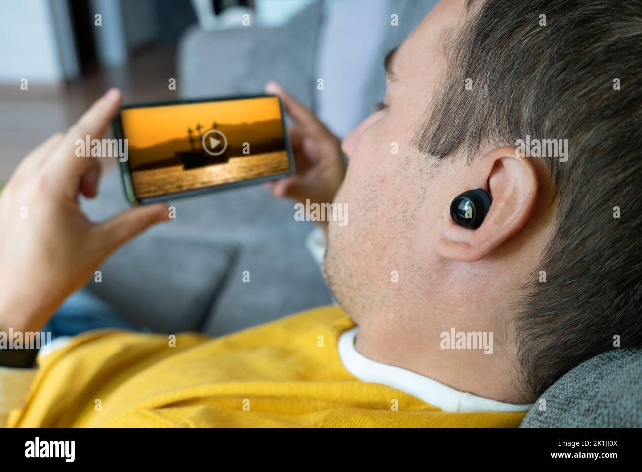 un giovane bellissimo uomo guarda un film sul suo smartphone. Visualizzazione di videoclip su Internet da parte di un utente. Ascolto di musica tramite telefono. Foto Stock