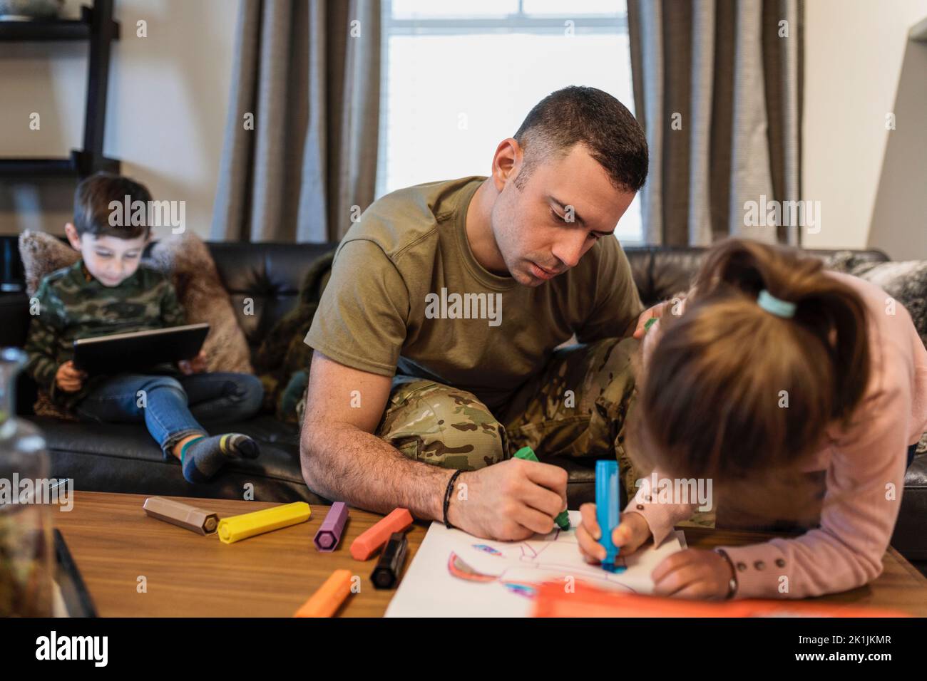 Soldato padre e figlia colorazione con pennarelli in soggiorno Foto Stock