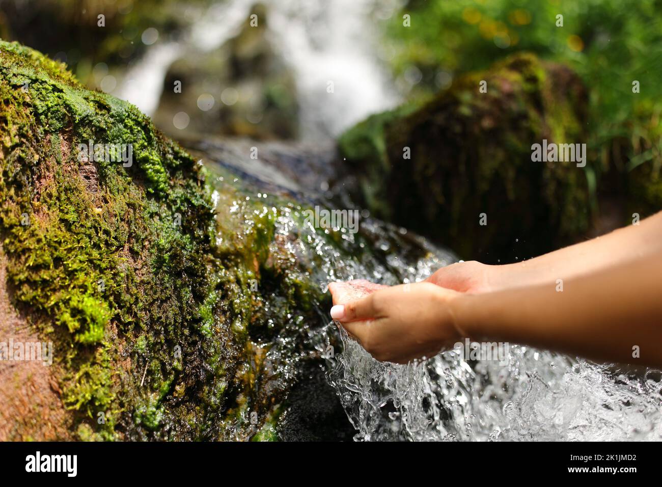 Primo piano ritratto di una donna mani in una cascata che cattura l'acqua non trattata Foto Stock