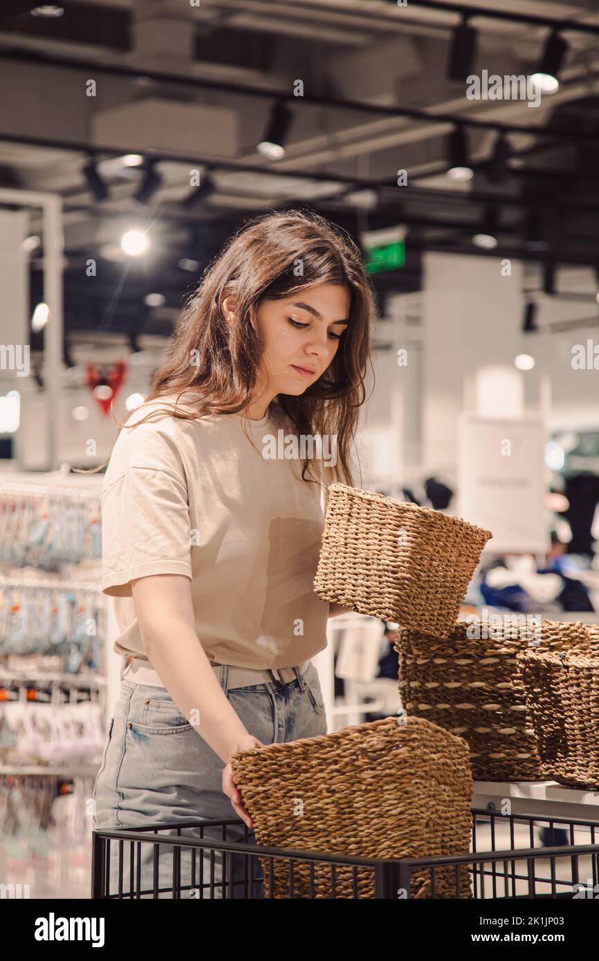 Una giovane donna sceglie i cestini per un interno domestico in un deposito domestico di miglioramento. Foto Stock