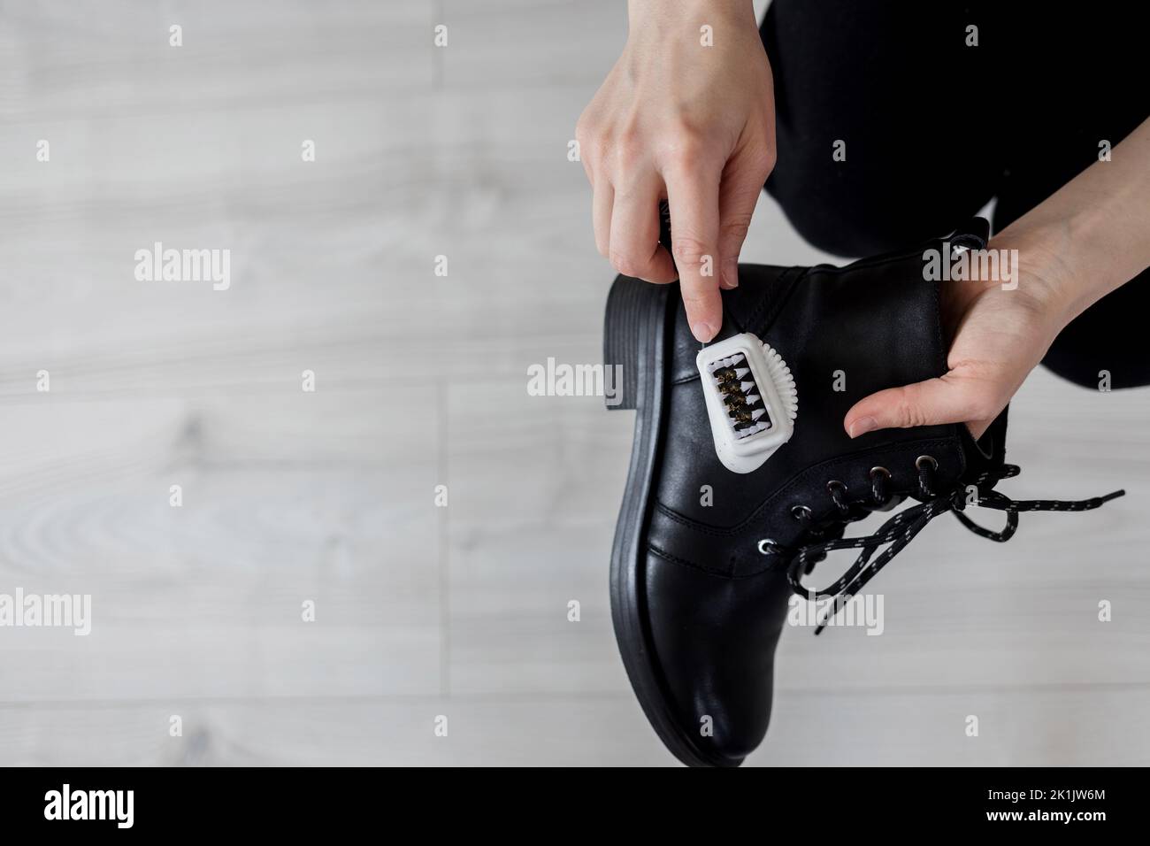 Donna pulizia scarpe in pelle nera. Cura delle scarpe con un prodotto speciale Foto Stock