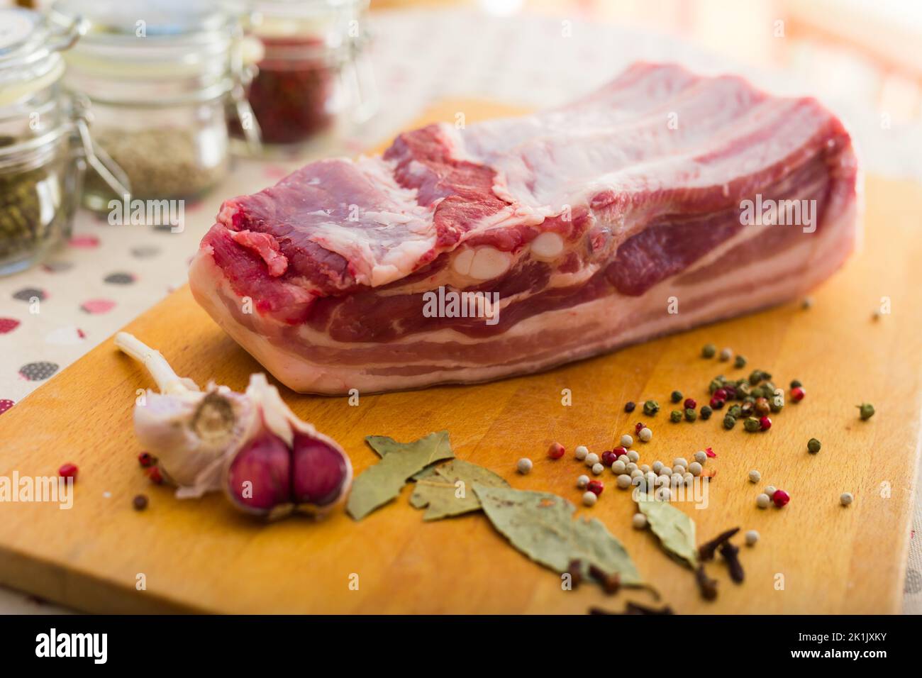 fresco pezzo di pancia di maiale su tavola di legno con spezie Foto Stock