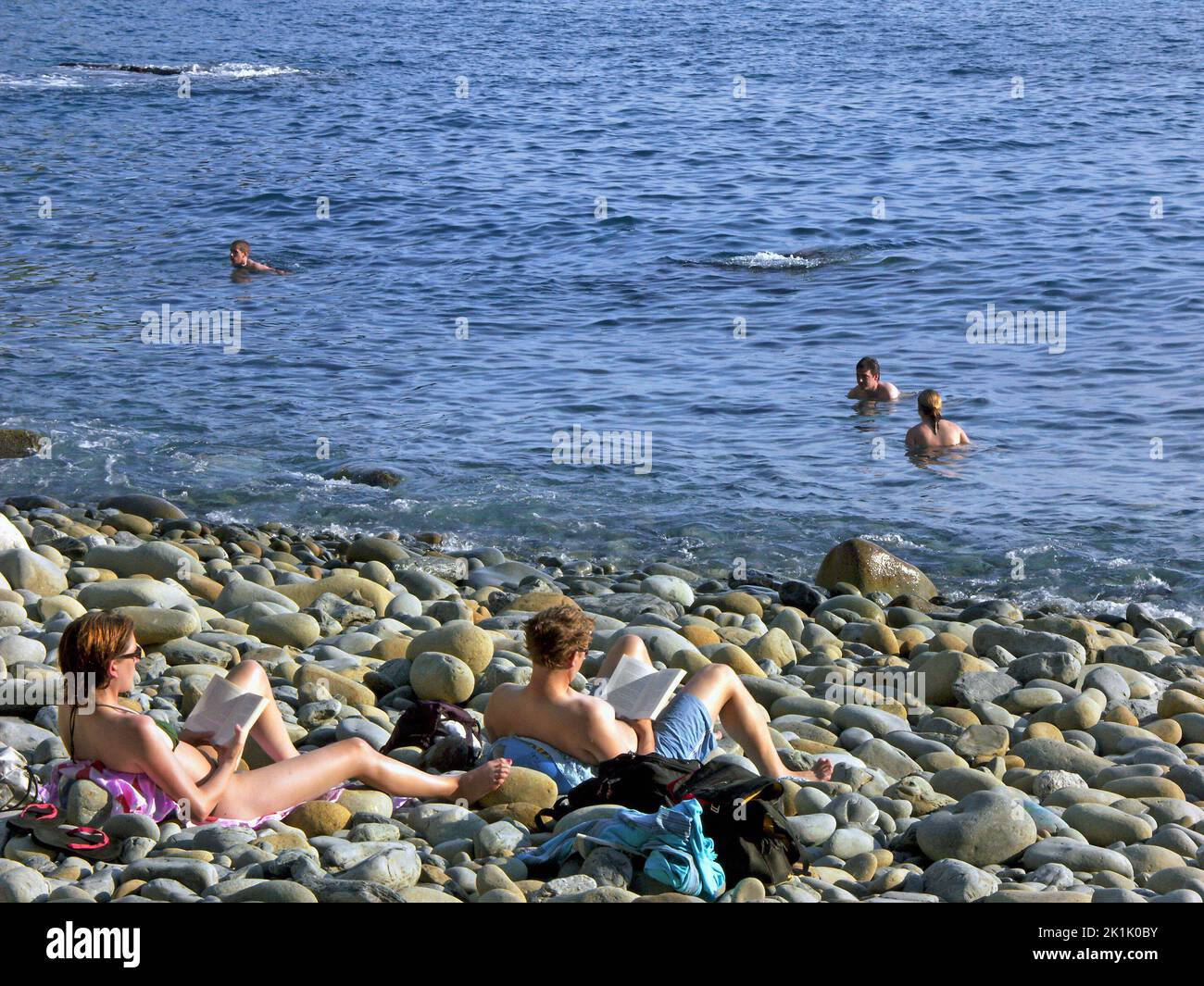 Gente che si crouola sulla spiaggia costiera, Riomaggiore, cinque Terre, Italia Foto Stock