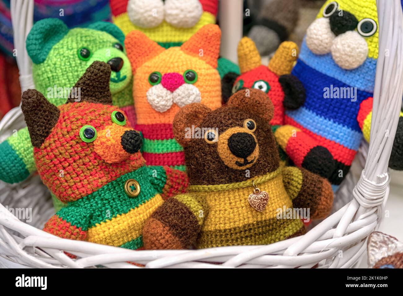 Giocattoli in maglia multicolore per bambini fatti a mano in cesto bianco. Animale giocattolo per bambini. Foto Stock