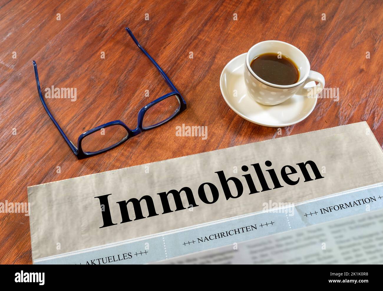 Quotidiano immobiliare con bicchieri e caffè su una scrivania Foto Stock