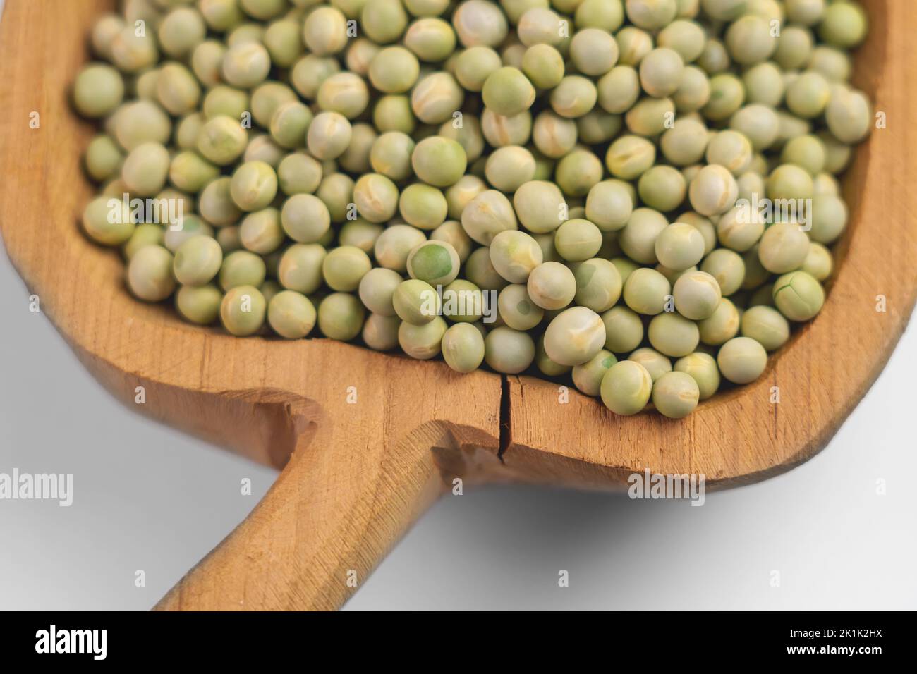 Ciotola rustica completamente scolpita con piselli secchi verdi su un primo piano di fondo bianco Foto Stock
