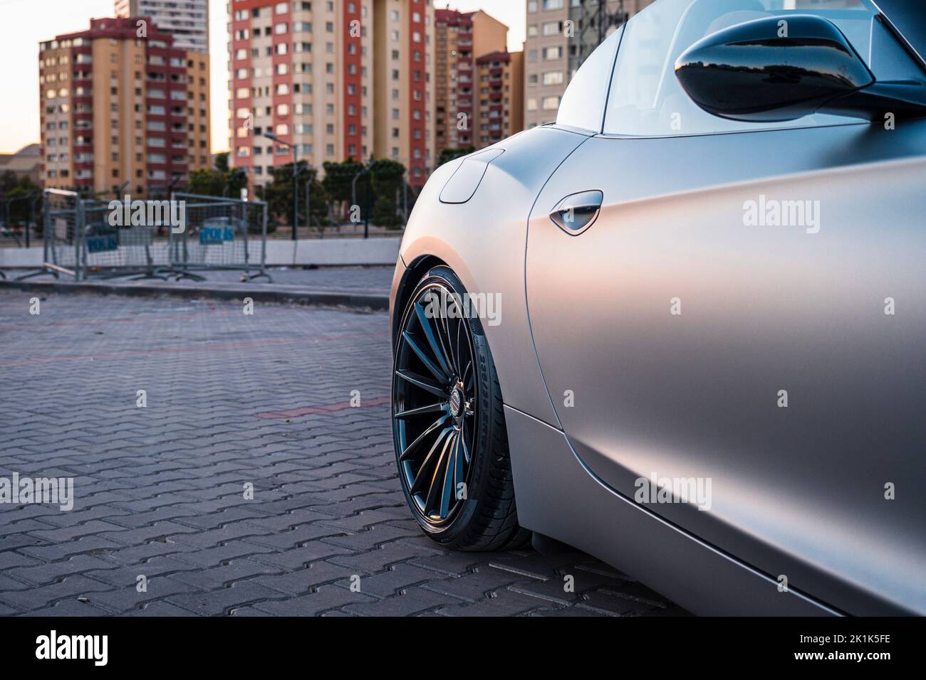 Auto sportiva convertibile con rivestimento grigio. Edifici e tramonto sullo sfondo. Foto Stock