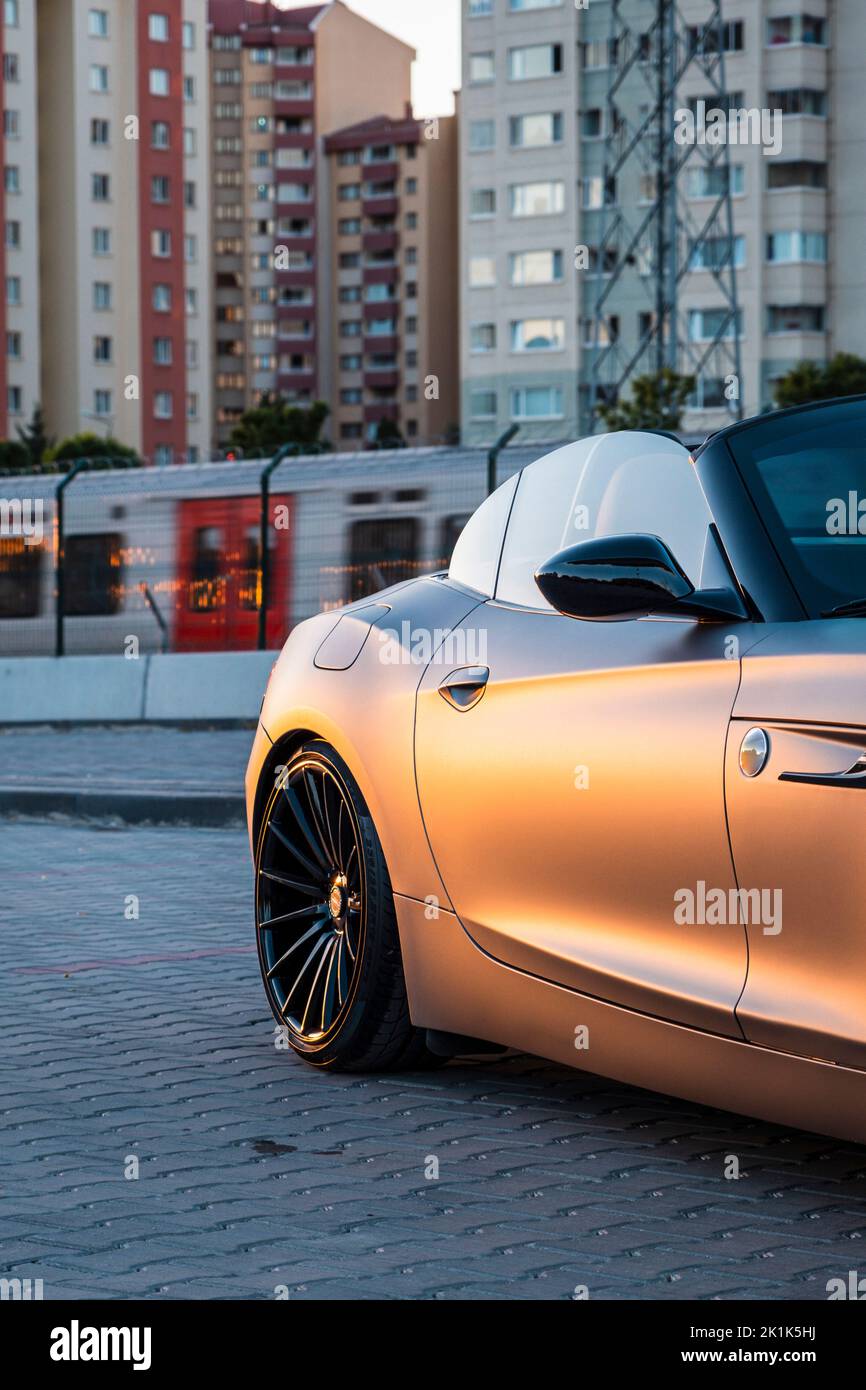 Auto sportiva convertibile con rivestimento grigio. La metropolitana passa dietro e ci sono dettagli dell'edificio. Foto Stock