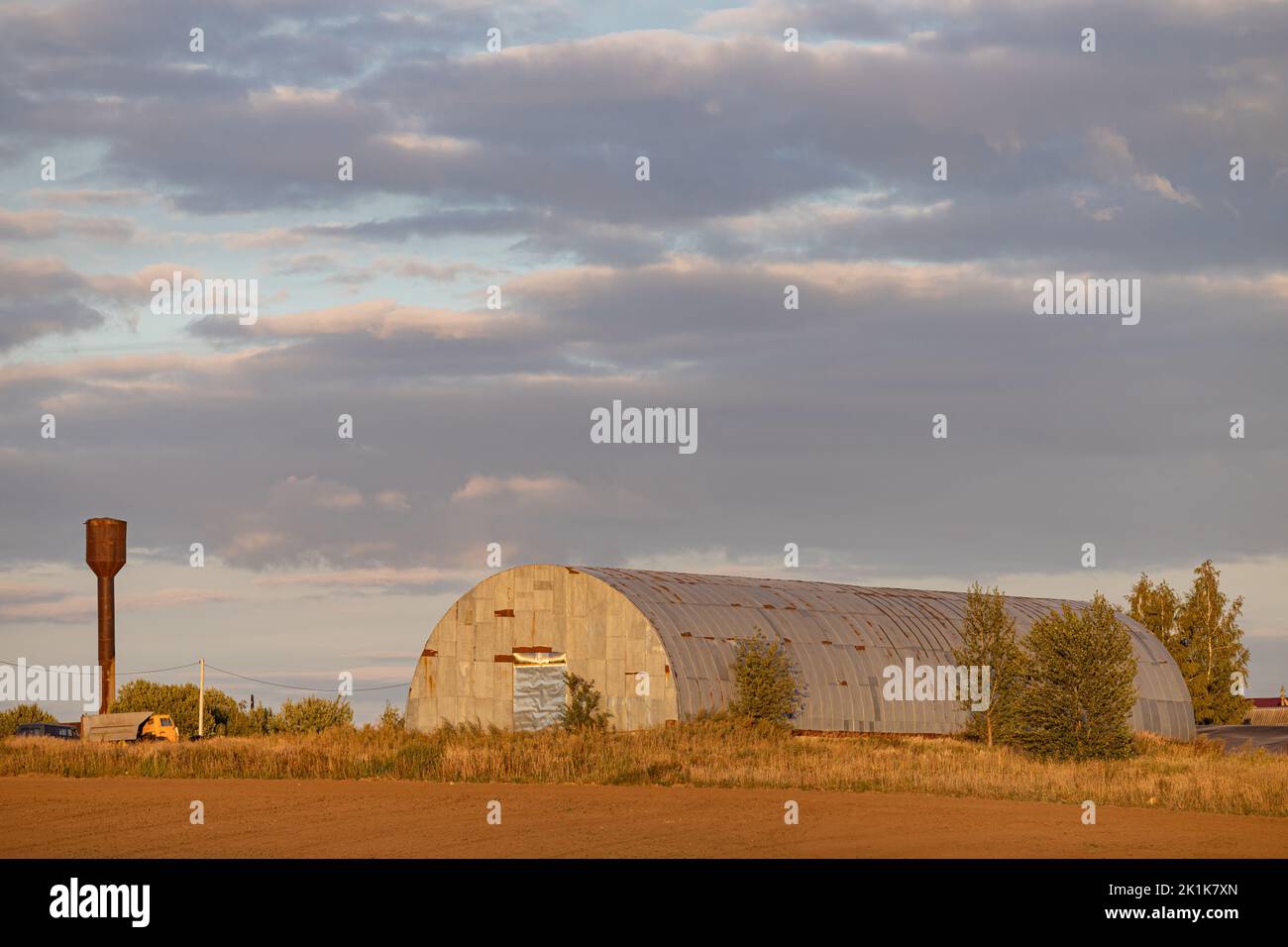 il vecchio hangar si trova sul campo la sera. il vecchio hangar per le attrezzature Foto Stock