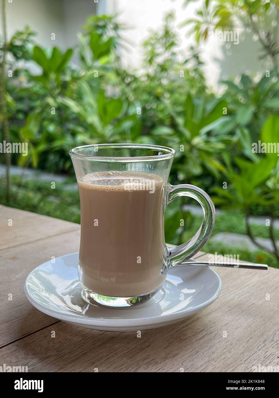 Bicchiere con tè al latte. Messa a fuoco selettiva sulla tazza in vetro. Foto Stock