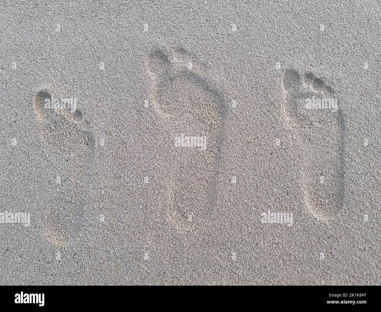 Tre impronte umane di varie dimensioni sulla sabbia di una spiaggia tropicale. Foto Stock