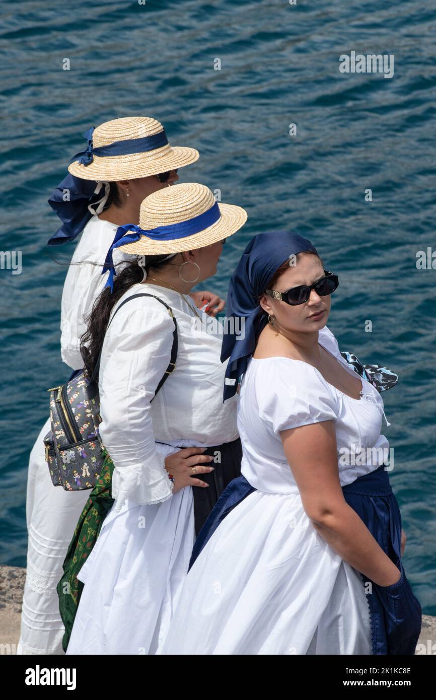 Tre donne in costumi locali tradizionali in piedi sul bordo del molo e in attesa che la celebrazione di iniziare, Romeria Barquera, Los Abrigos Foto Stock