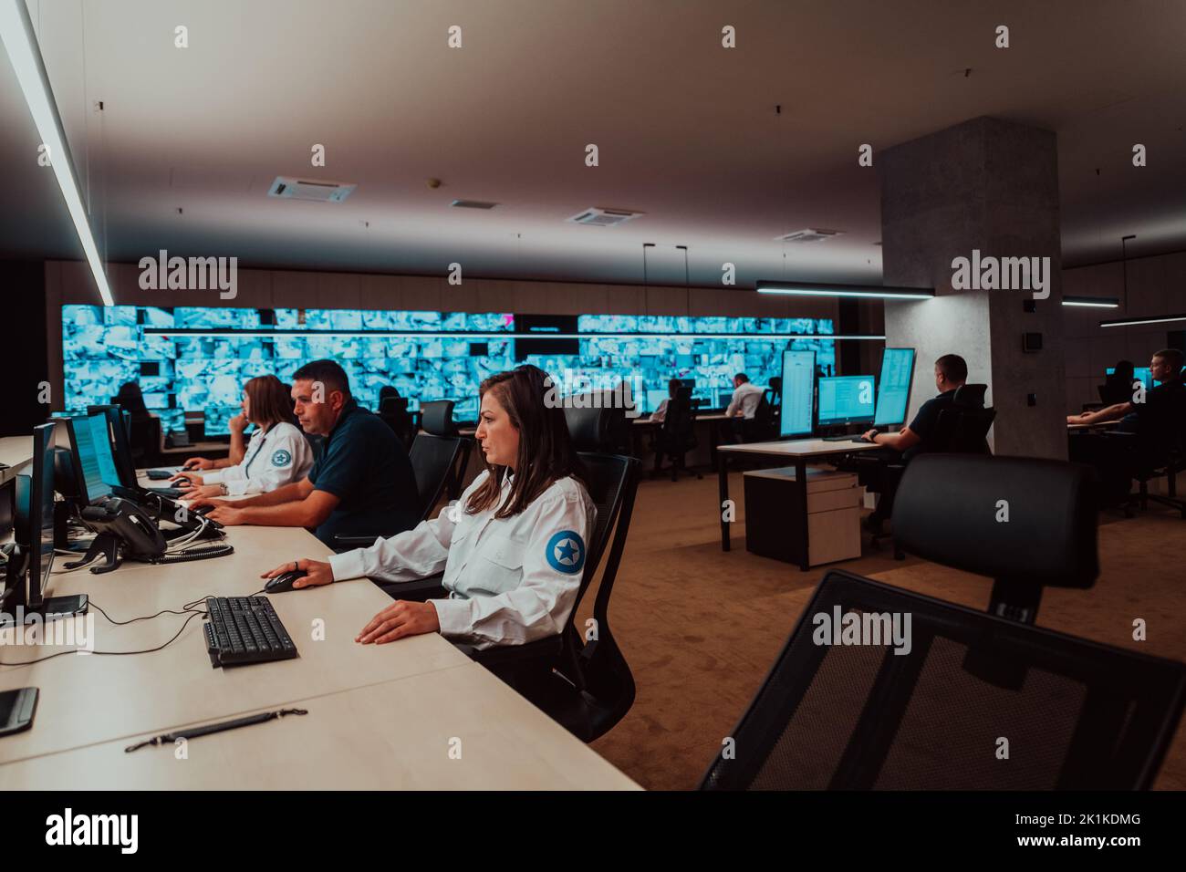 Gruppo di operatori del data center di sicurezza che lavorano in una sala di monitoraggio TVCC alla ricerca di più monitor funzionari che monitorano più schermi per Foto Stock