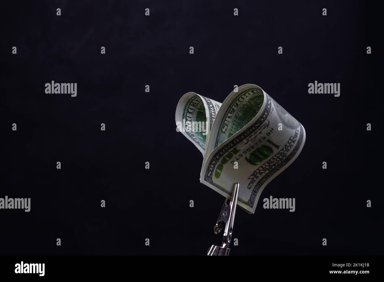 Primo piano il detentore di denaro contorto centinaia di dollari. Isolato su sfondo nero. Foto Stock