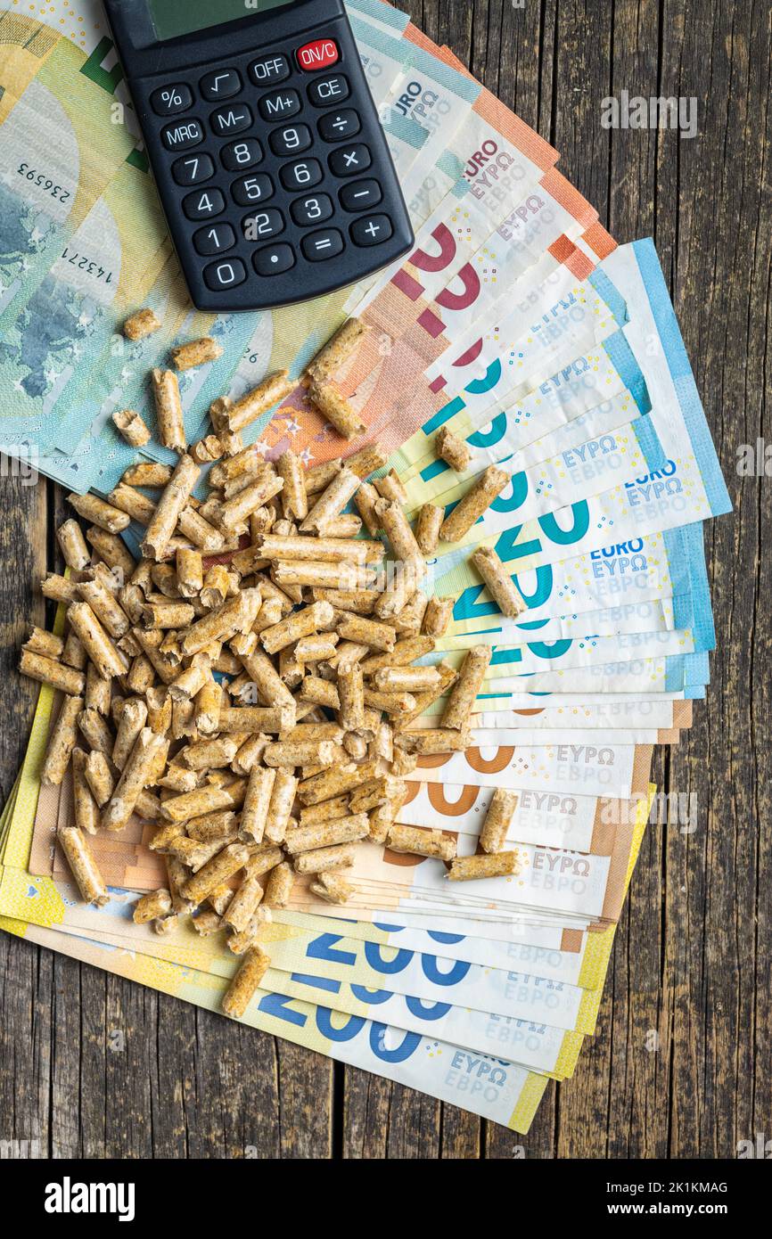 Pellets di legno, calcolatrice e moneta in euro. Concetto di aumento dei prezzi dell'energia. Vista dall'alto. Foto Stock