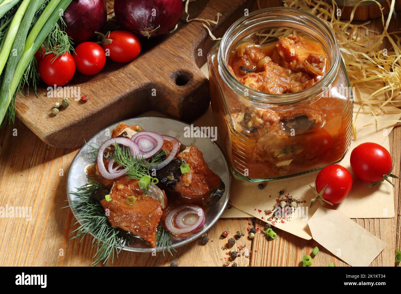 Pesce gatto inscatolato in pomodoro su un tavolo di legno in un vaso di vetro Foto Stock