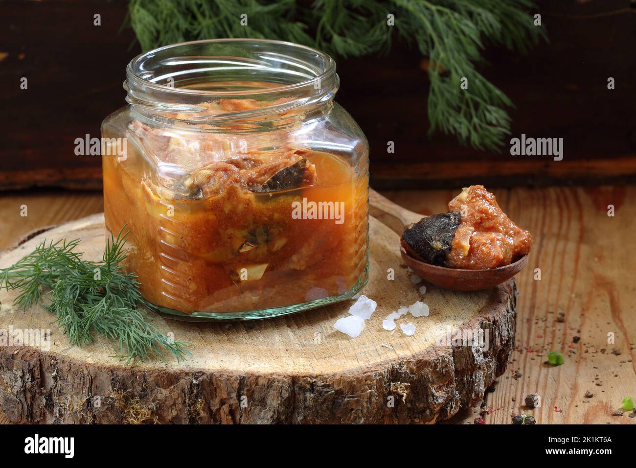 Pesce gatto inscatolato in pomodoro su un tavolo di legno in un vaso di vetro Foto Stock