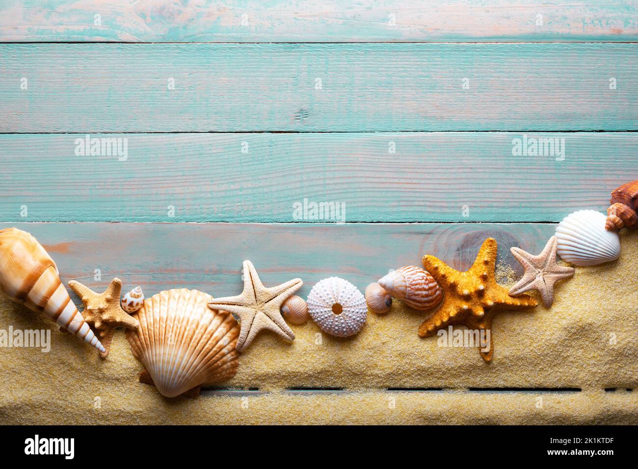 Vacanza e concetto estate con stelle marine e conchiglie su un tavolo in legno turchese con sabbia Foto Stock