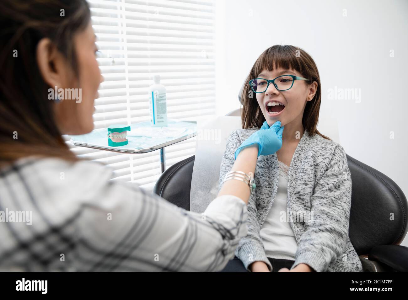 Ortodontista che esamina la paziente della ragazza nella stanza dell'esame della clinica Foto Stock