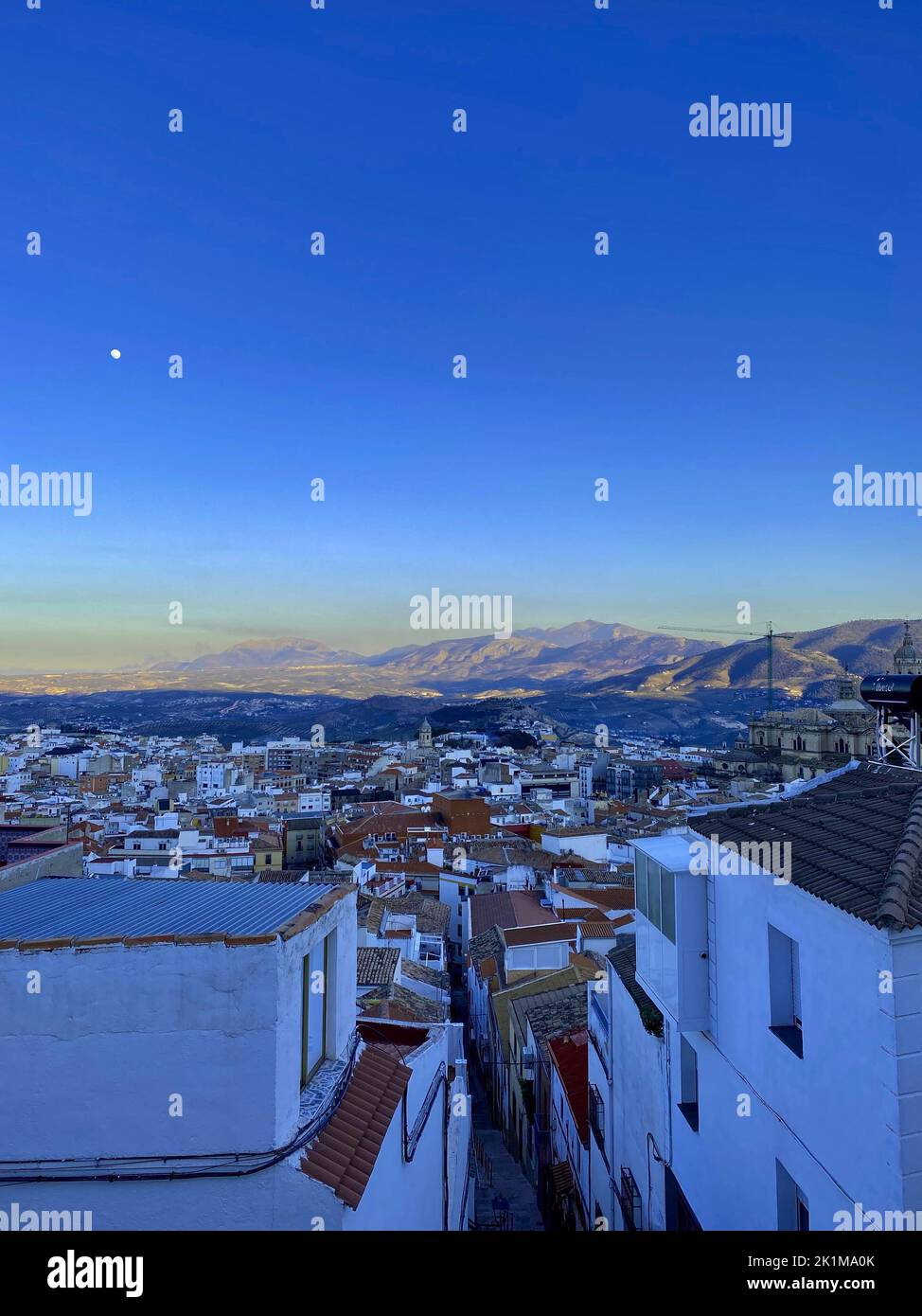 Vista ad alto angolo della città di Jaen, tipico edificio bianco, cielo blu, luna e montagne sullo sfondo. Foto di alta qualità Foto Stock