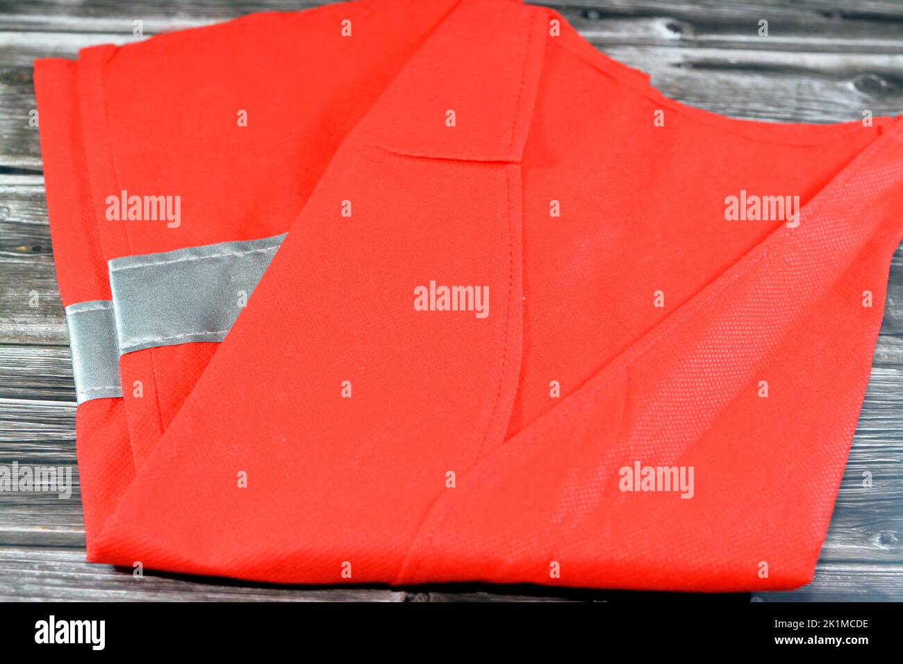 Giubbotto di sicurezza rosso riflettente con strisce riflettenti isolate su sfondo di legno, giubbotto leggero per lavori di costruzione, conducenti, lavoratori della strada e. Foto Stock