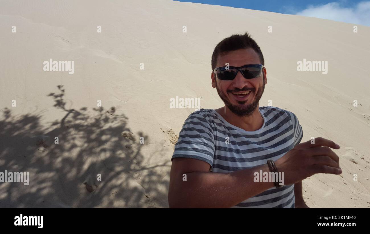 Un uomo che corre, saltando e divertendosi tra le dune. Foto Stock