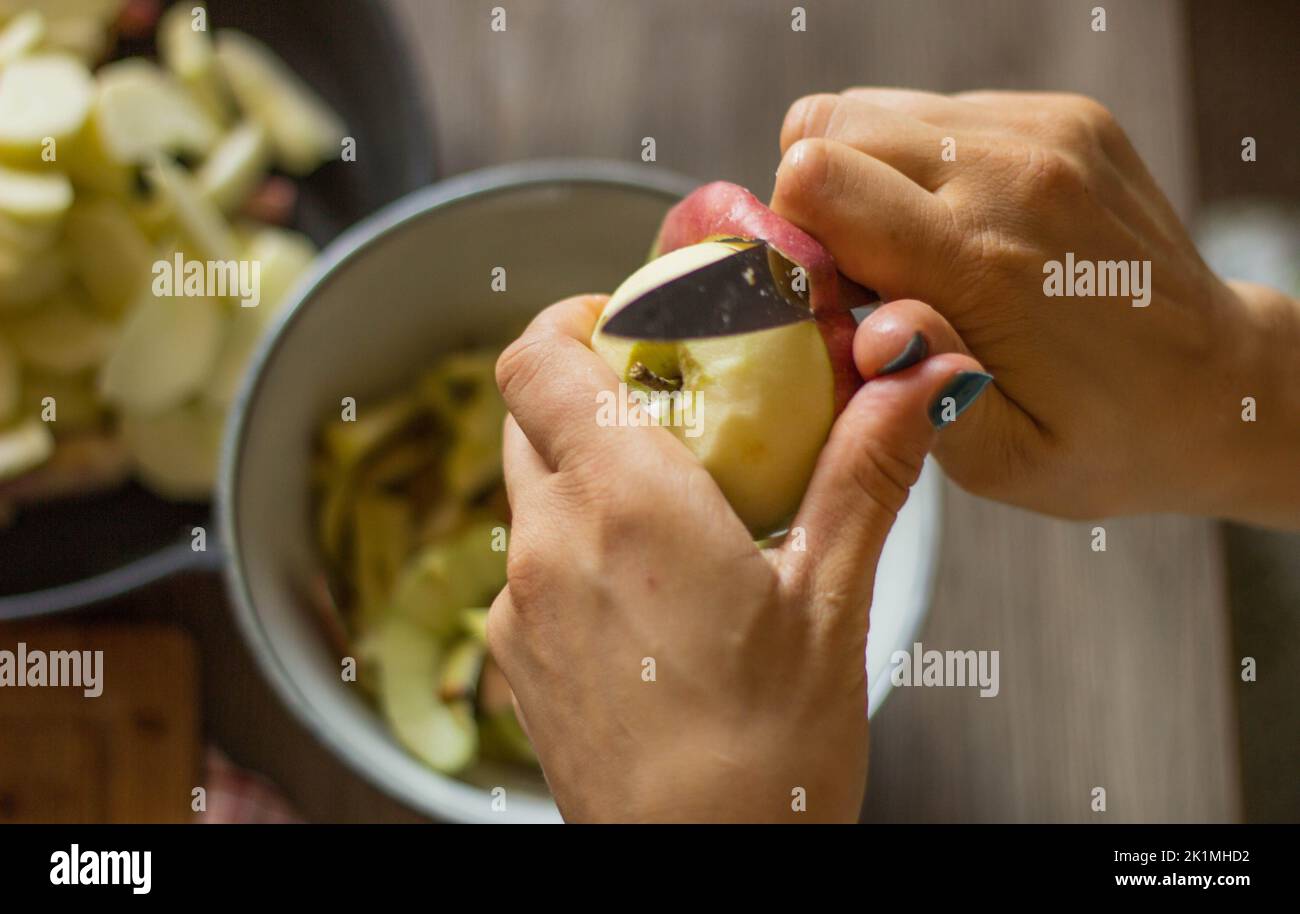 Le mani di una donna che sbuccia una mela per una torta Foto Stock