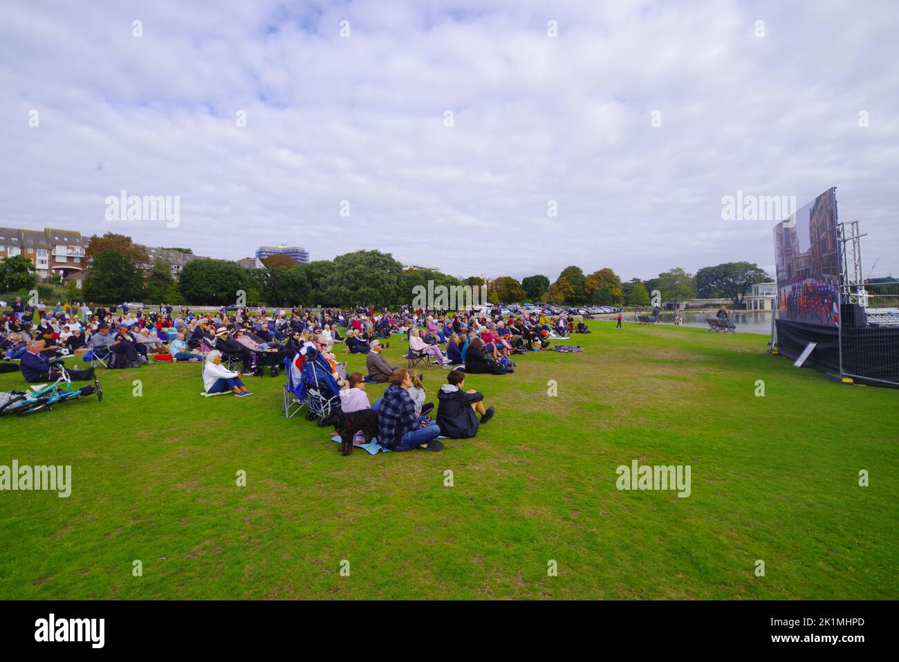 Centinaia di persone si sono riunite a Poole Park Dorset per guardare sul grande schermo i funerali della Regina Elisabetta II 19/09/2022 . I funerali della Regina dall'Abbazia di Westminster e la marcia funeraria al Castello di Windsor sono stati mostrati su grandi schermi in tutto il Regno Unito. Poole Park ha visto un grande raduno di persone che hanno guardato i funerali attraverso il grande schermo e più tardi hanno mostrato i loro rispetti in piedi per l'inno nazionale. Foto Stock