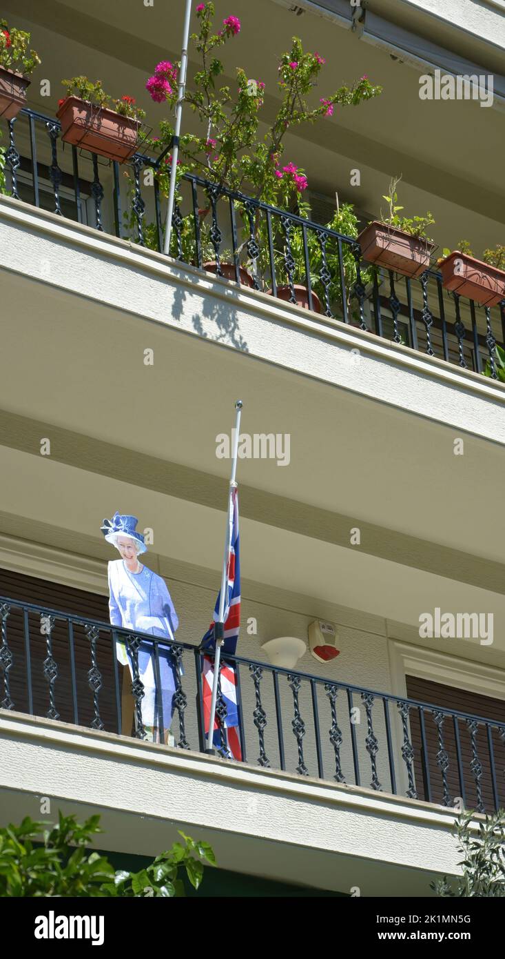 Una foto a grandezza naturale della regina Elisabetta II e una bandiera britannica a mezza altezza, su un balcone il giorno del funerale della regina Foto Stock