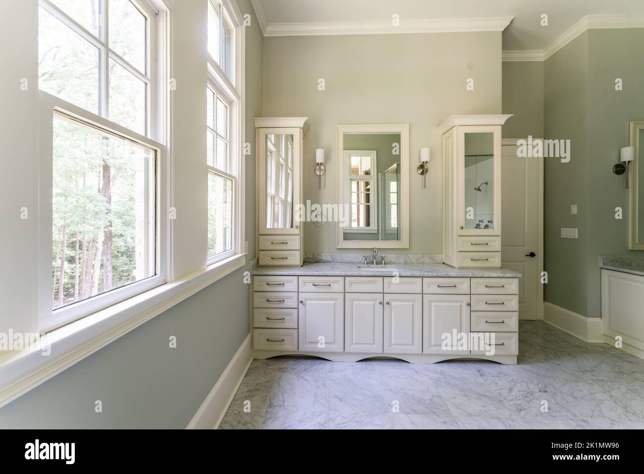 Bagno verde salvia con finiture bianche dover, vasca indipendente, doccia chiusa con vetro con mattoni a spina di pesce dipinti in bianco, piano di granito Foto Stock