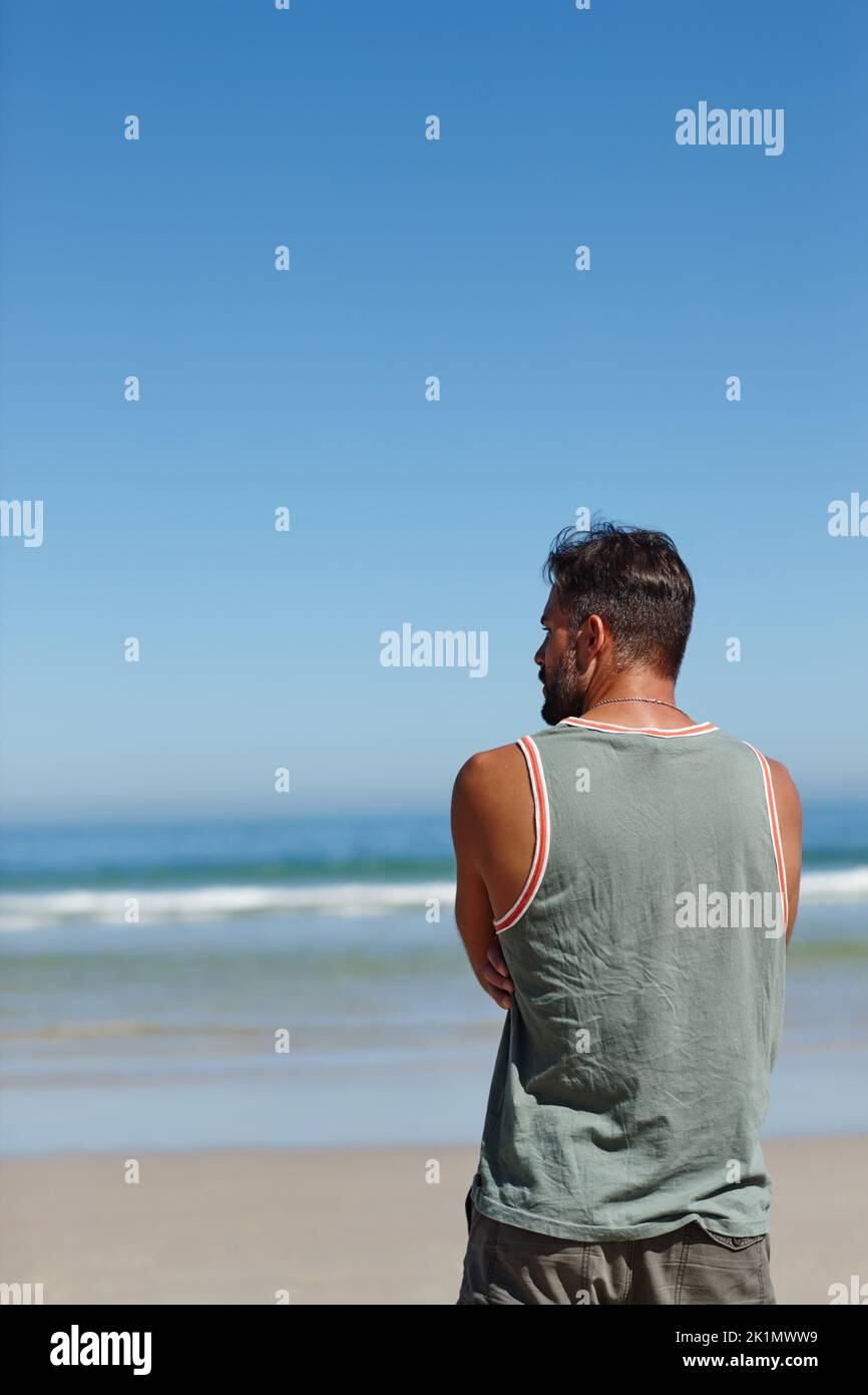 Ora questo è un po 'di tempo spiaggia. Ripresa da dietro di un giovane uomo che guarda l'oceano. Foto Stock