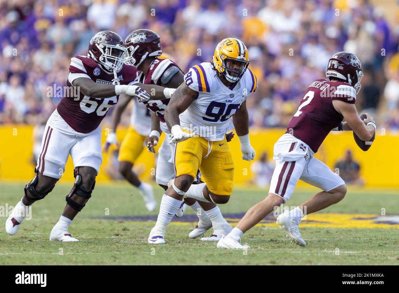 Mississippi state Bulldogs quarterback Will Rogers (2) si rimescolano dalla tasca mentre LSU Tigers difensive affrontare Jacobian Guillory (90) precipita il pa Foto Stock