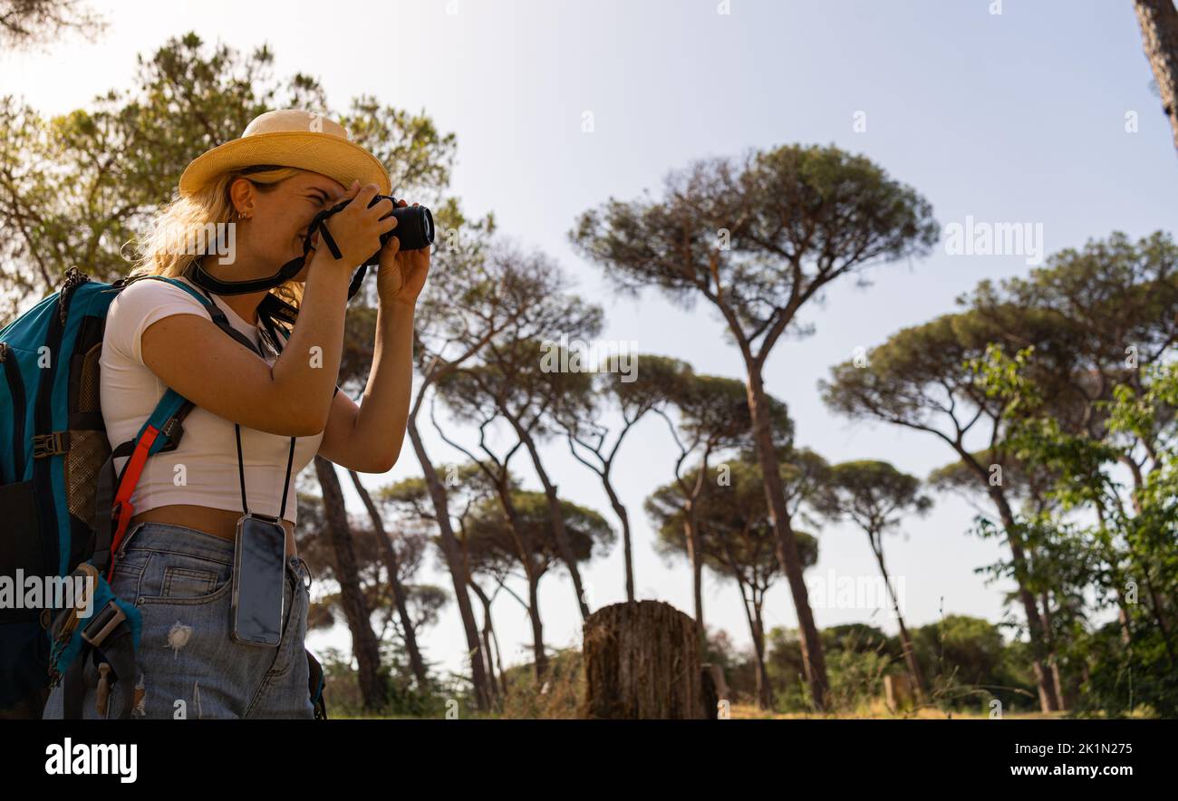 Una giovane donna sorridente esplora la giungla e scatta foto della fauna selvatica Foto Stock