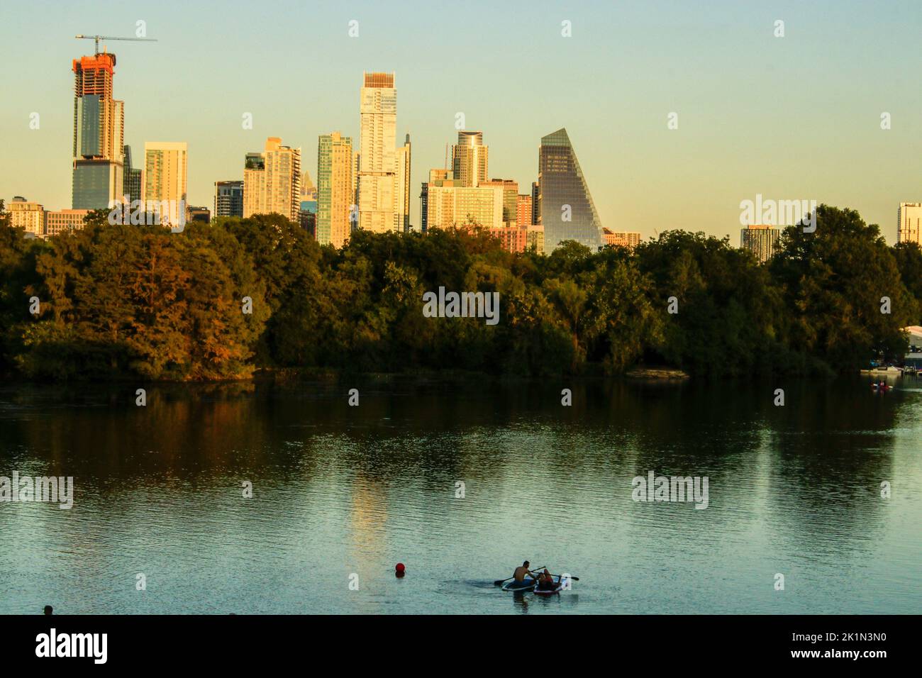 Persone che cavalcano paddle board sul fiume Colorado per una vista al tramonto della città di Austin, Texas Foto Stock