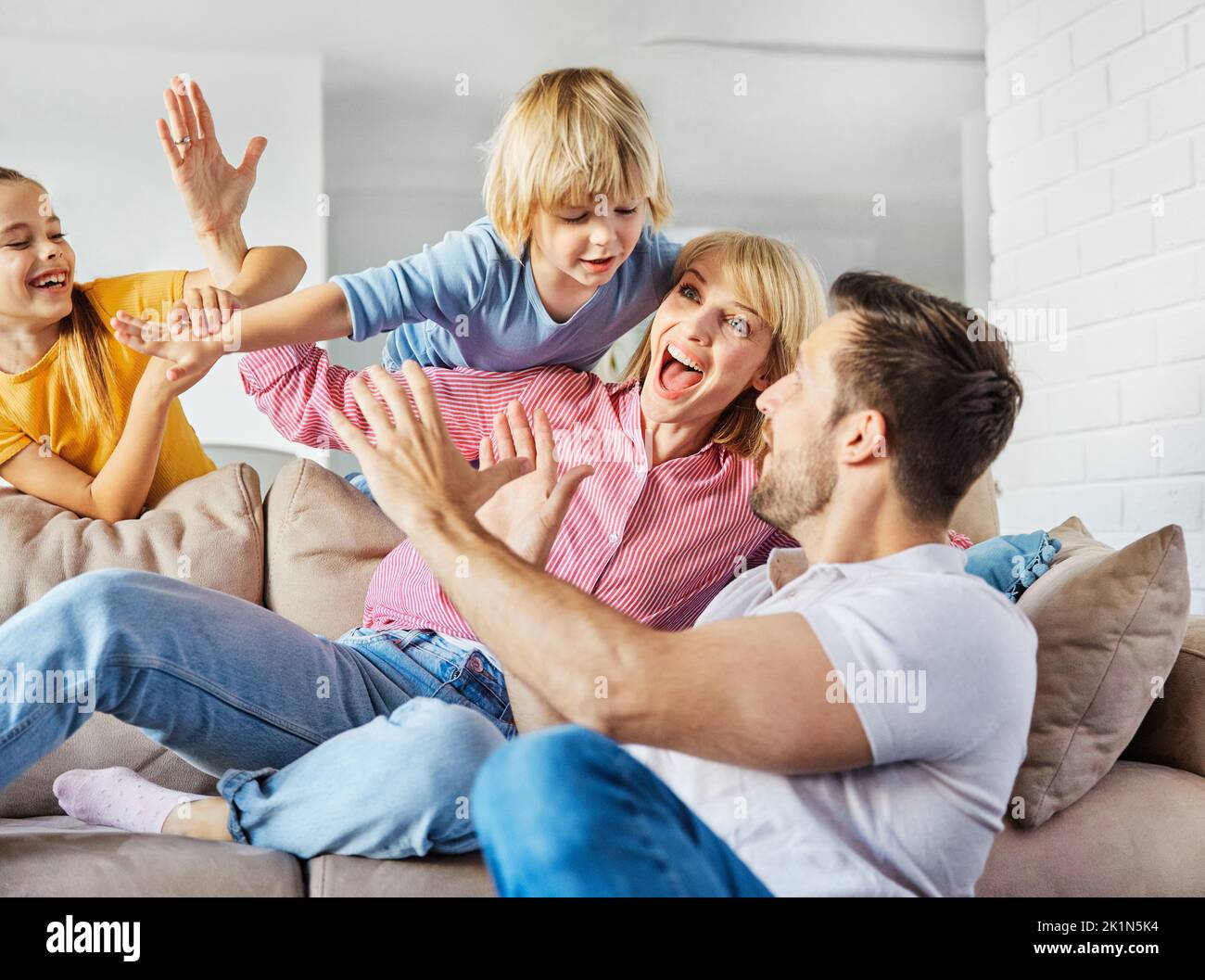 bambino figlia figlio famiglia felice madre padre divano giocare divertimento insieme ragazza ragazzo allegro sorridente casa Foto Stock