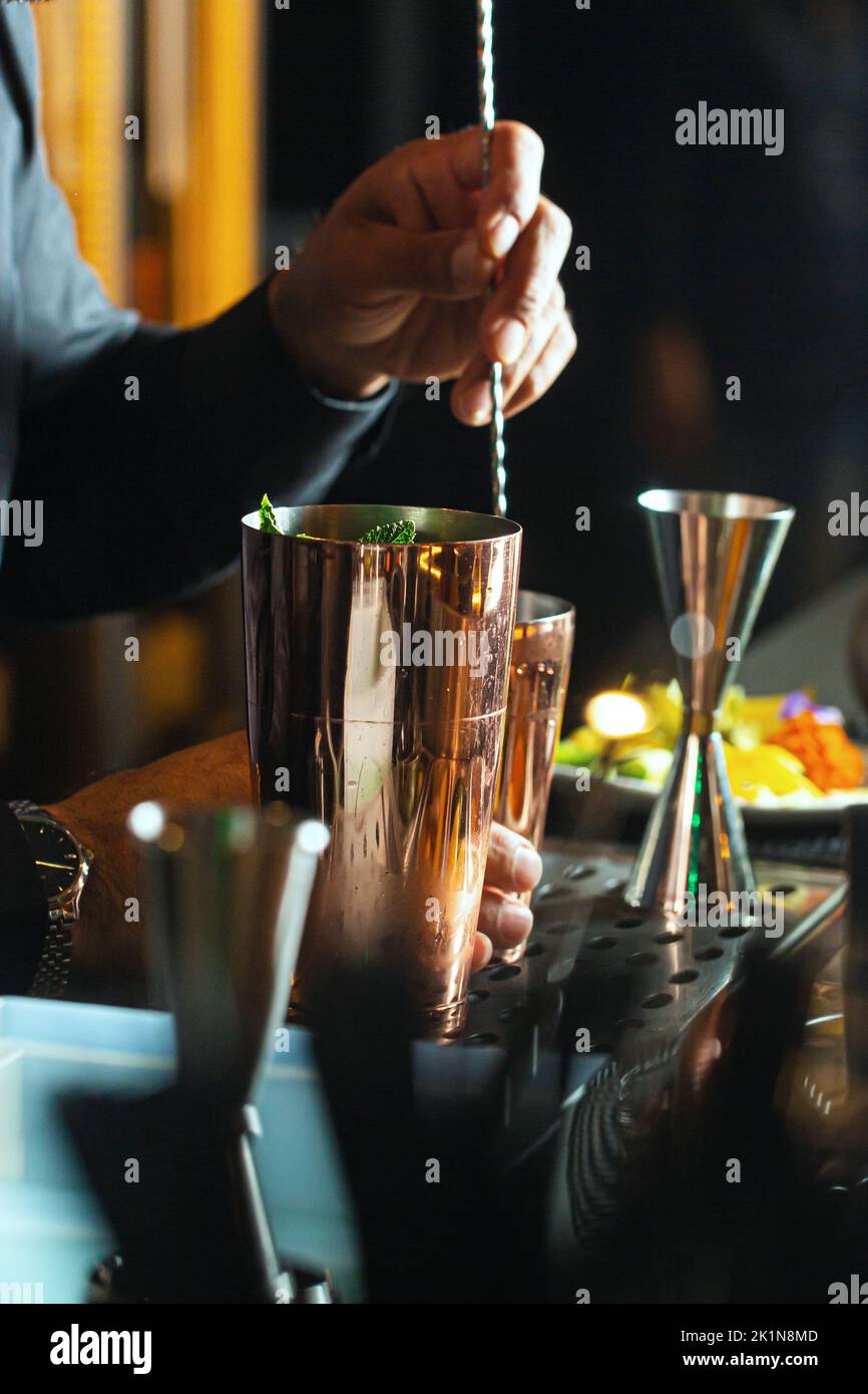 Il barista prepara un cocktail in un ristorante utilizzando il cucchiaio Foto Stock