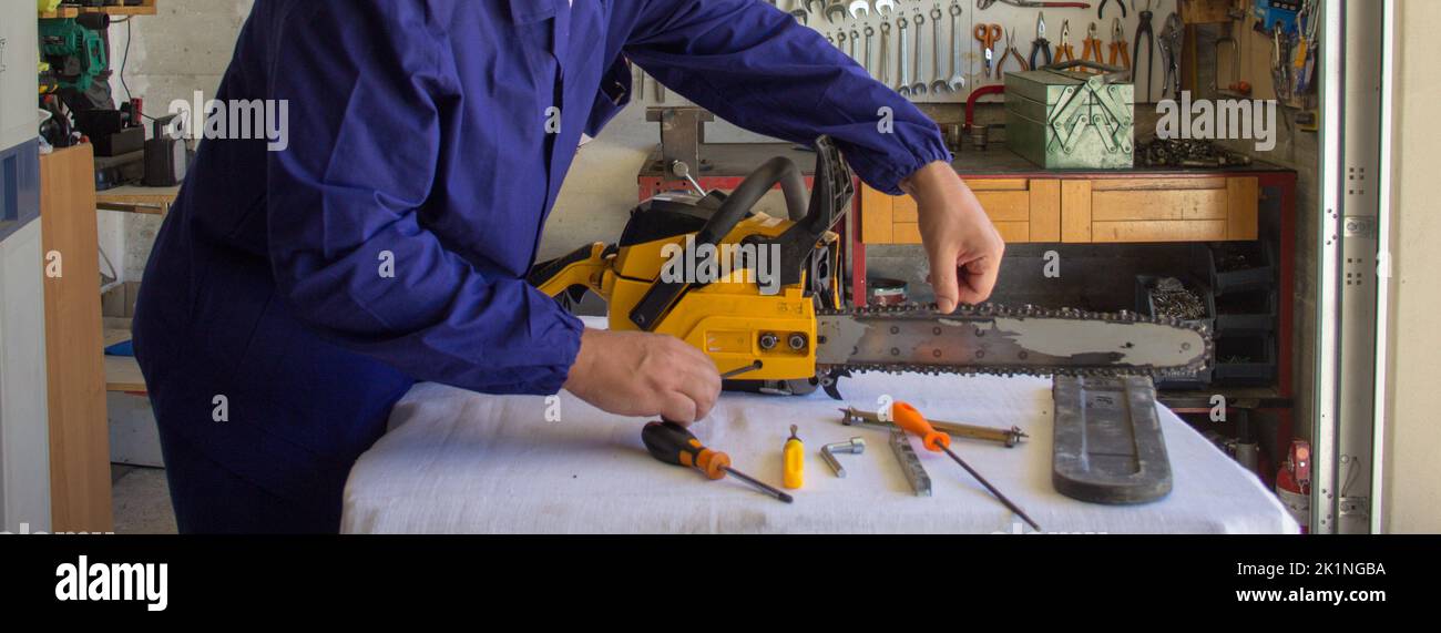 Immagine delle mani di un meccanico che ripara una motosega regolando la tensione della catena. Fai da te in previsione dell'inverno. Banner orizzontale Foto Stock