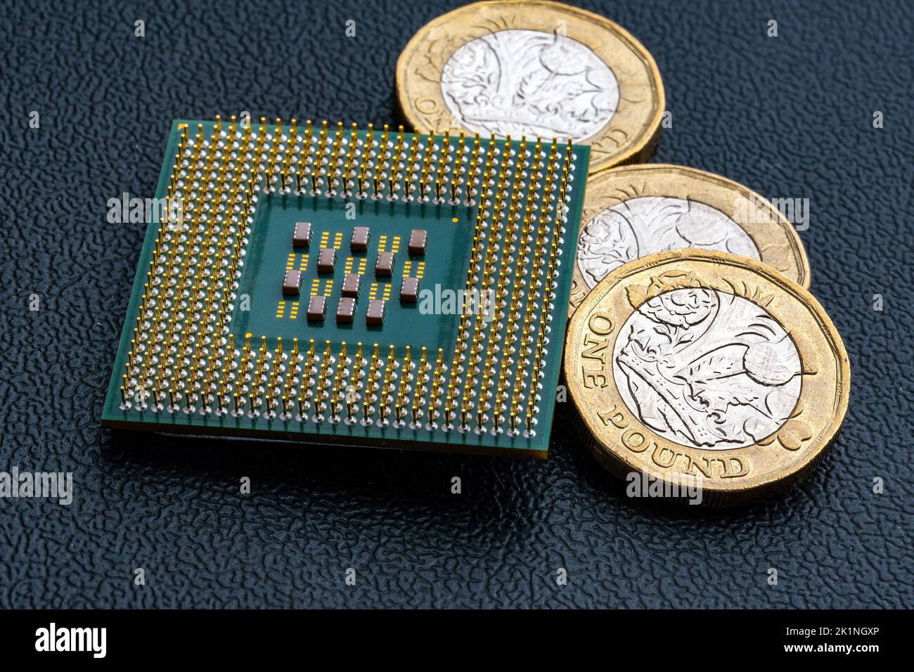 CPU con chip per computer di grandi dimensioni e monete da sterline britanniche. Concetto per microchip e denaro. Macro, messa a fuoco selettiva. Foto Stock