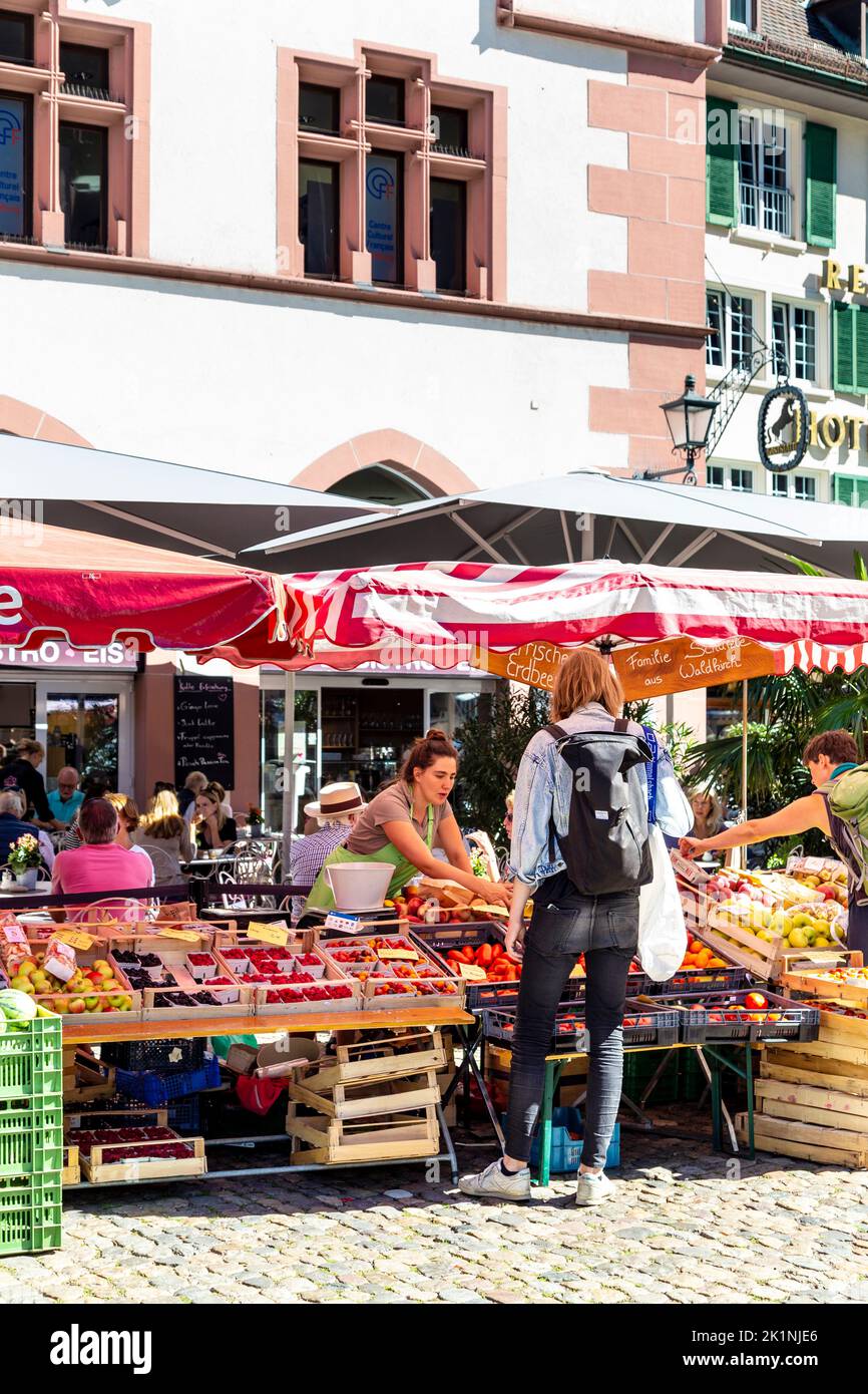 La gente che acquista in una bancarella di frutta e verdura al mercato di Münstermarkt sul Münsterplatz, Friburgo in Breisgau, Germania Foto Stock