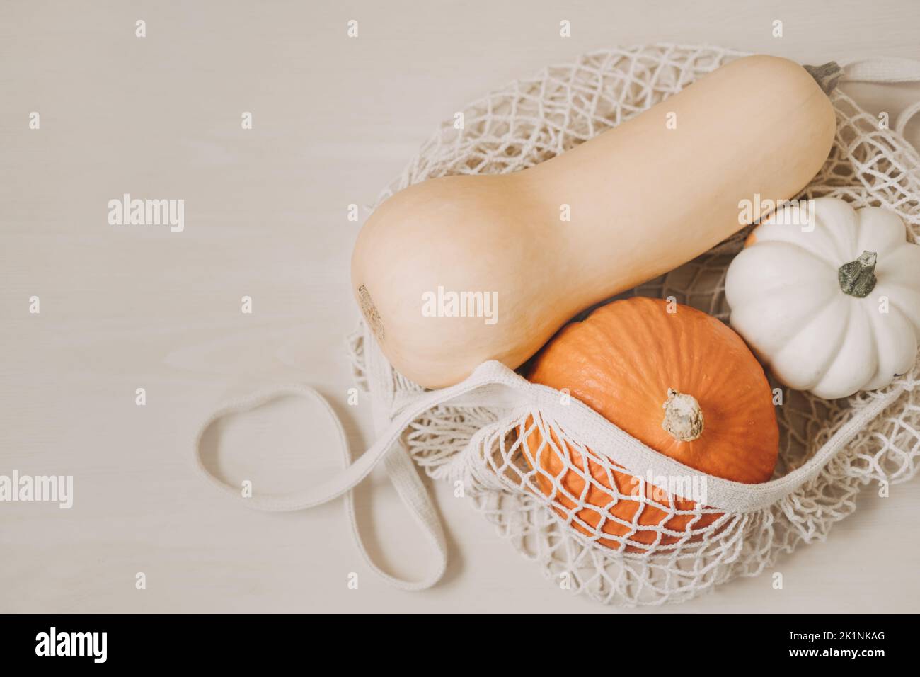 Sacco in rete di cotone senza scarti con zucche diverse sul tavolo. Autunno zucca di ringraziamento sfondo con zero rifiuti sacco riutilizzabile con zucche su Foto Stock