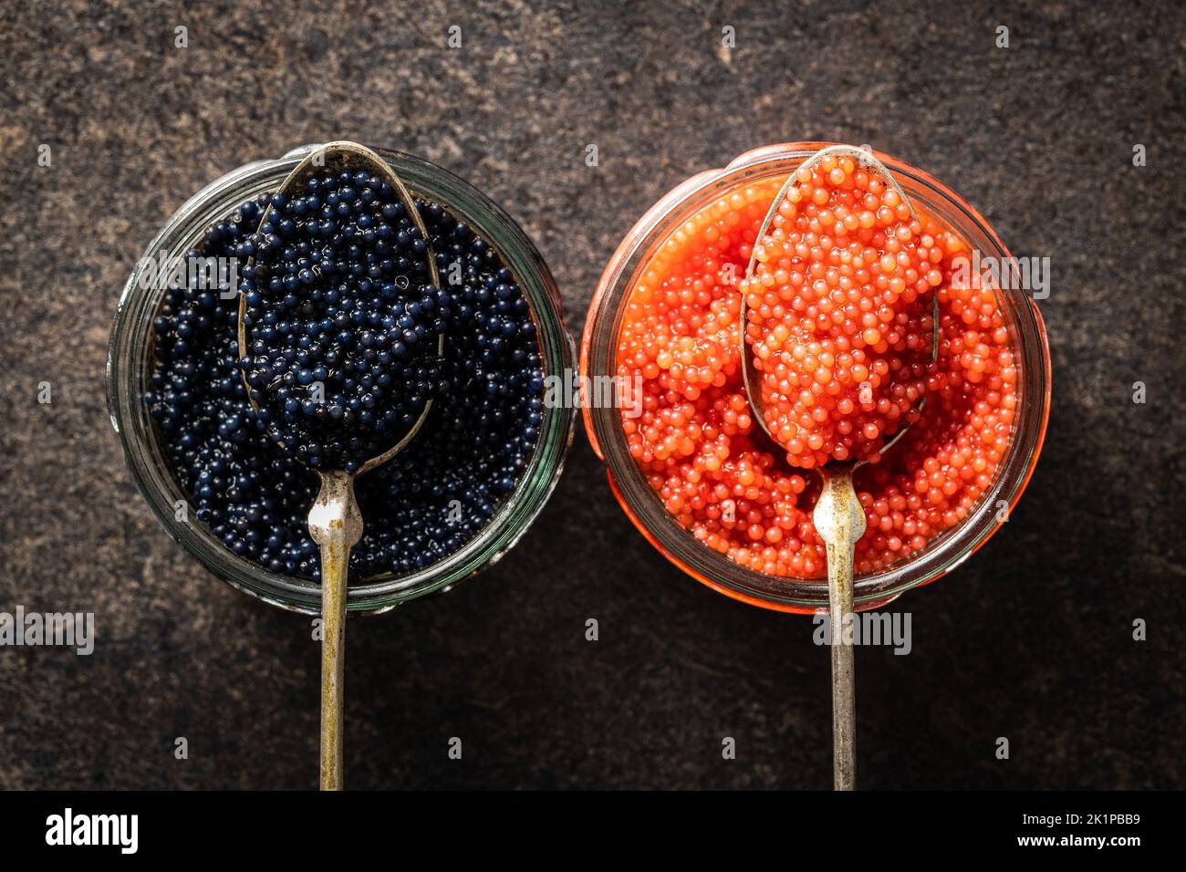 Caviale rosso e nero in cucchiai d'argento sul tavolo scuro. Vista dall'alto. Foto Stock