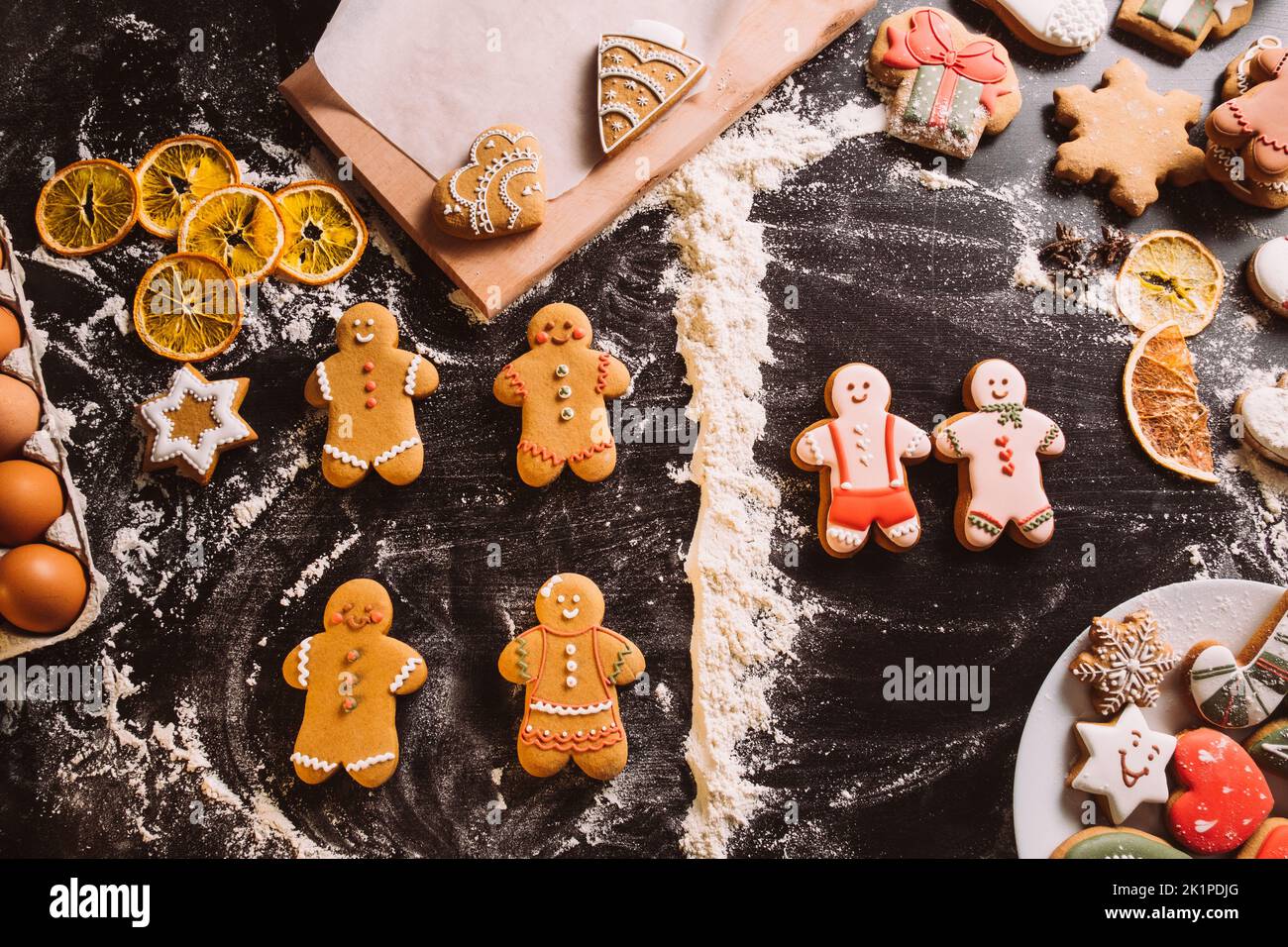 Buon giorno di San Valentino. Biscotti decorati nei giorni festivi. Gingerbread uomini glassa colorata amata coppia divisa altri biscotti farina polvere linea sulla scrivania nera. Foto Stock
