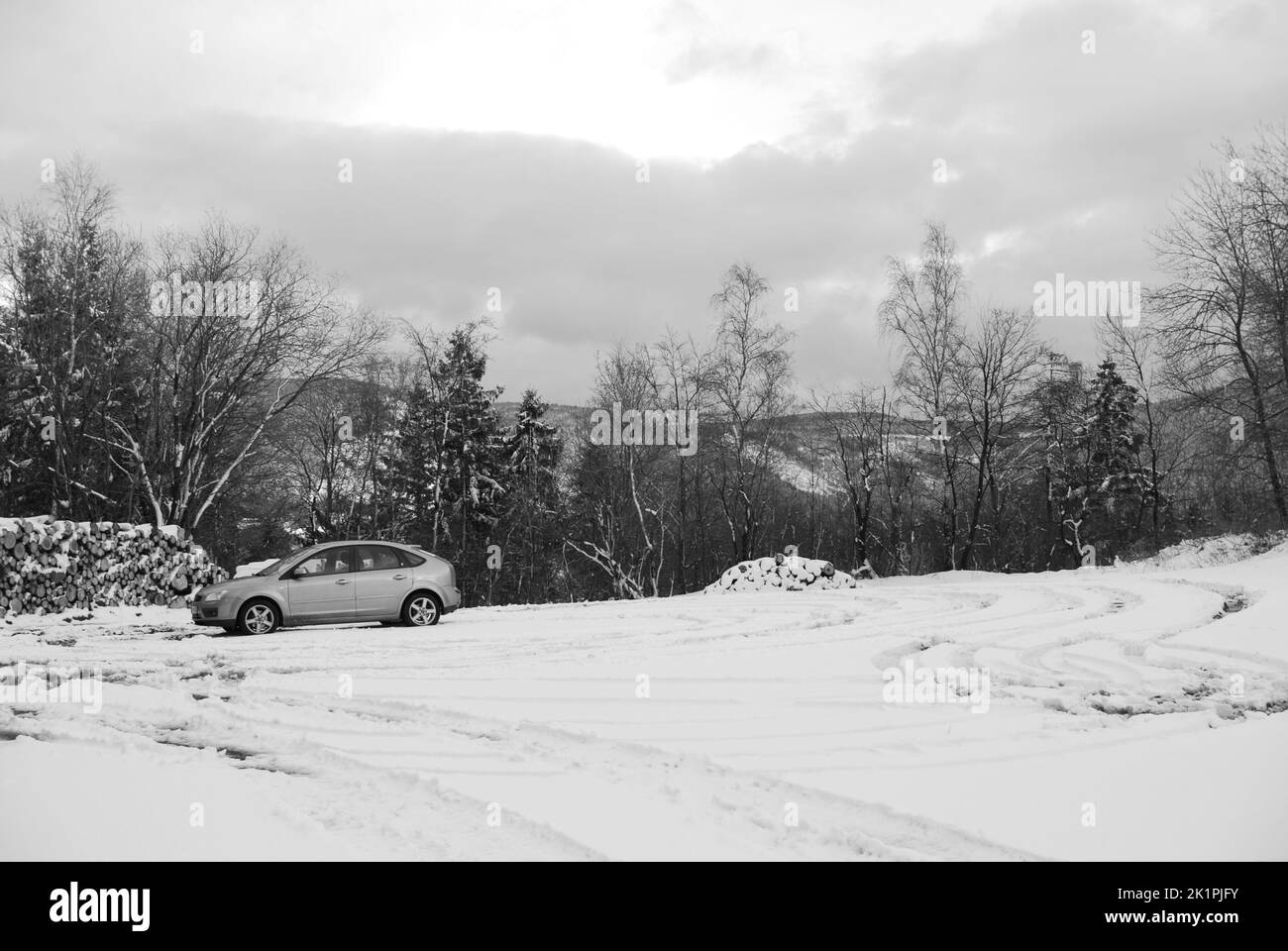 Una macchina grigia che guida su un sentiero attraverso una foresta bianca innevata Foto Stock