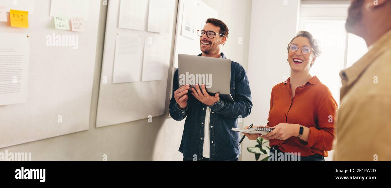 Buon uomo d'affari sorridente allegro mentre si incontra in un luogo di lavoro creativo. Gruppo di diversi imprenditori che analizzano un po 'di marketing repor Foto Stock
