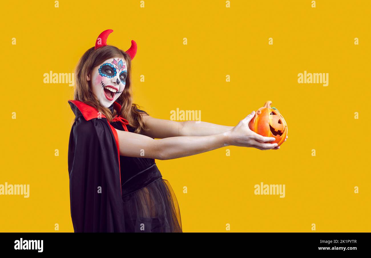 Allegra ragazza teenage creativa in costume diavolo su Halloween divertirsi su sfondo arancione. Foto Stock